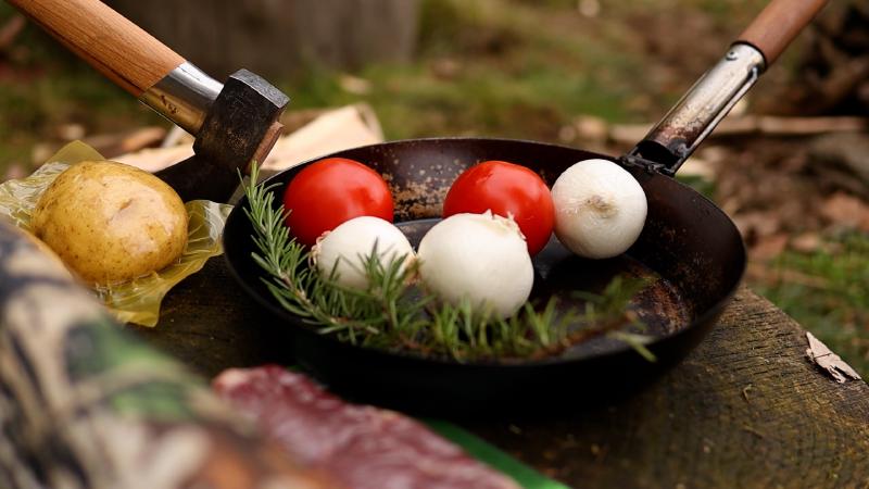 Tomatoes, mushrooms and rosemary in the cast iron pan — dinner prep over the fire