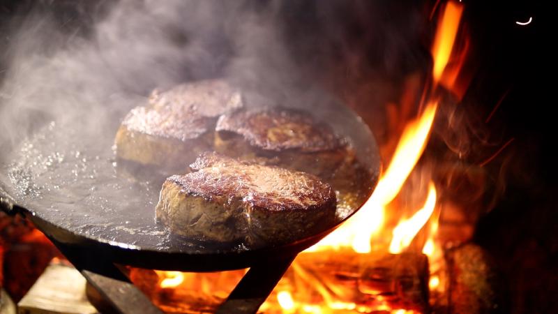 Steaks in the carbon steel pan, straight over the fire