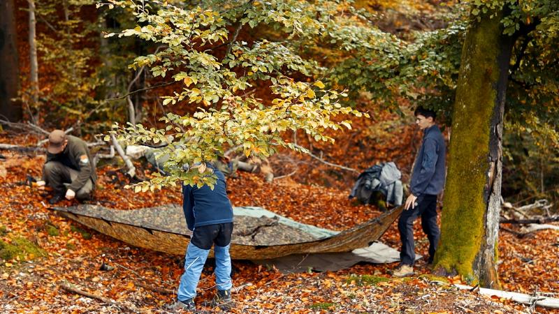 Setting up the camo tarp together in the autumn forest