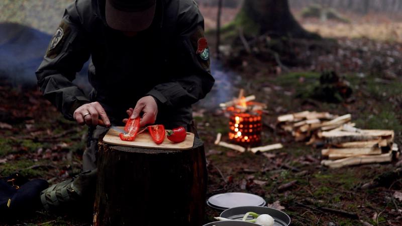 Chopping bell peppers on a tree stump – the X-FIRE 19 campfire glowing in the background