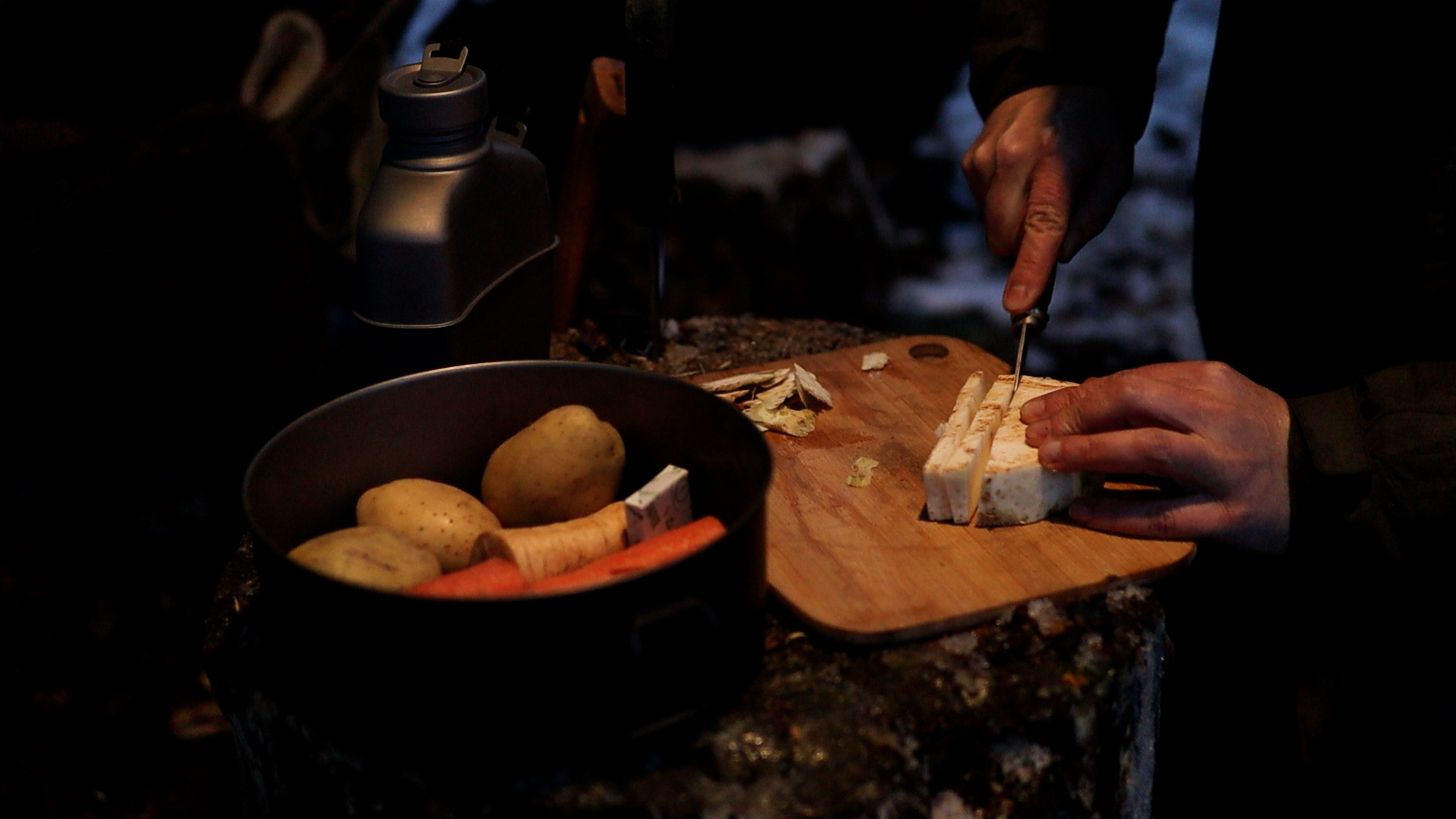 Kartoffeln, Möhren und Sellerie werden am Lagerfeuer für das Abendessen vorbereitet – Outdoorkochen im Winterlager