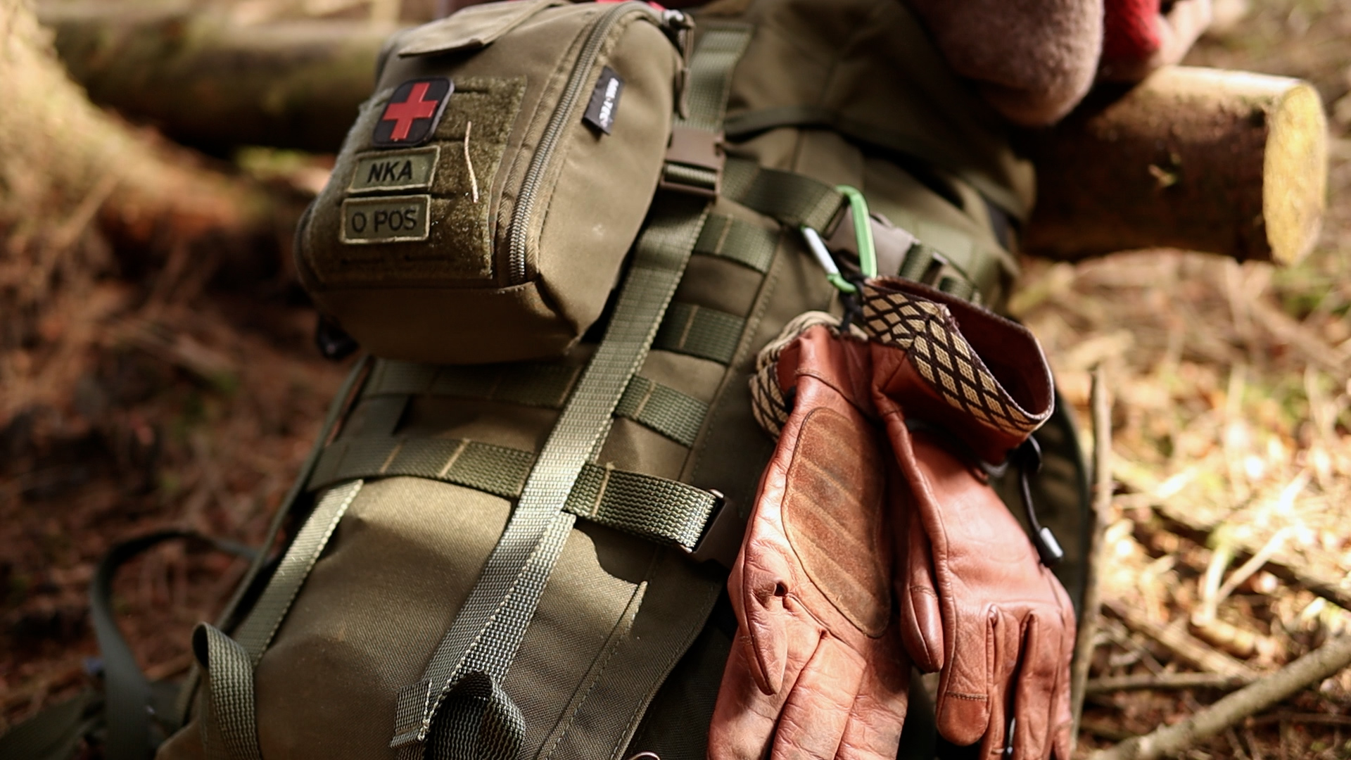 Detailaufnahme des Rucksacks und IFAK am Lagerplatz im Wald