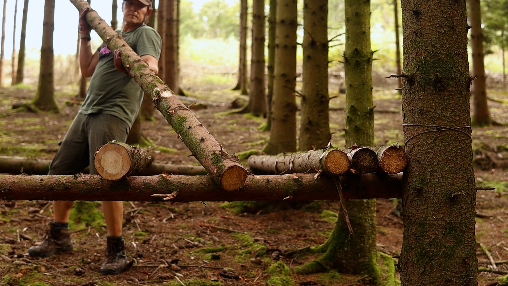 Aufgeschichtete Stämme formen die Basis des erhöhten Bushcraft-Betts
