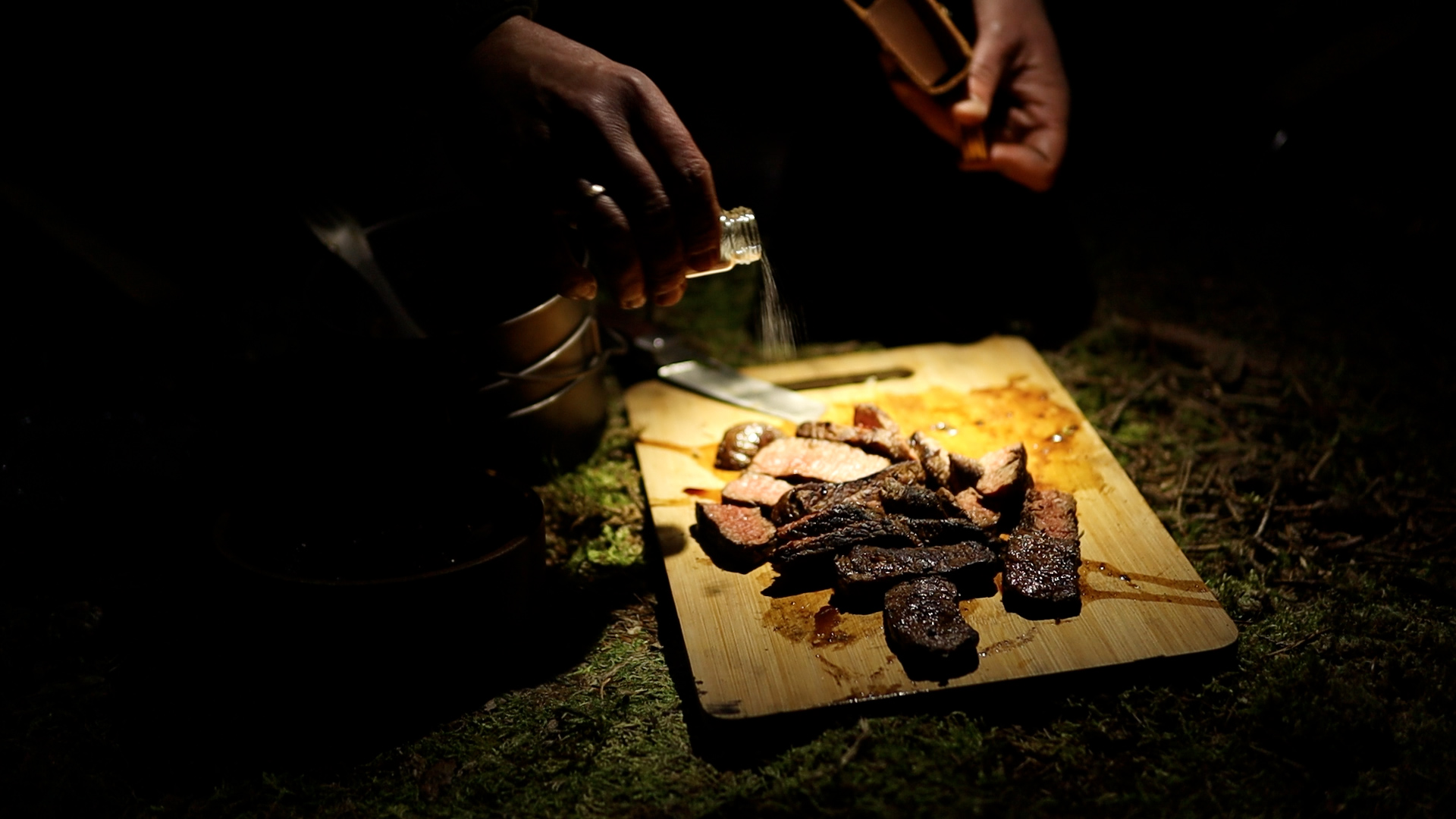 Aufgeschnittenes Steak auf Schneidebrett wird gesalzen beim Bushcraft-Camp