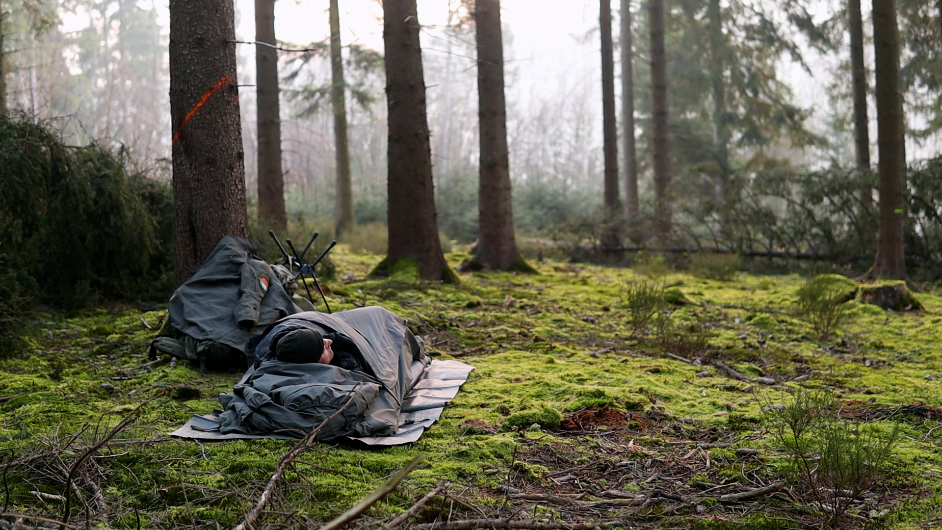 Bushcrafter schläft im Biwaksack auf dem moosigen Waldboden