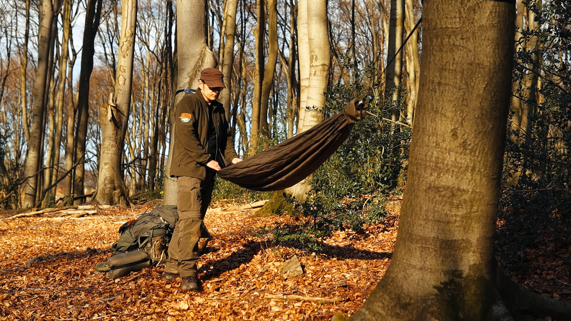 Simon hängt die onewind Hängematte zwischen zwei Buchen im Laubwald auf