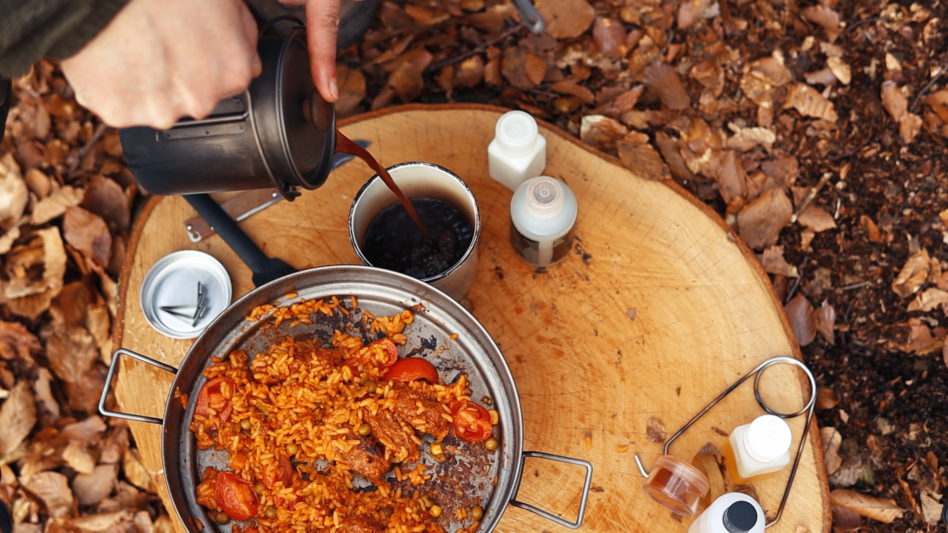 Bestargot Titan French Press gießt Kaffee in Becher, daneben Reisgericht auf Baumscheibe im Wald