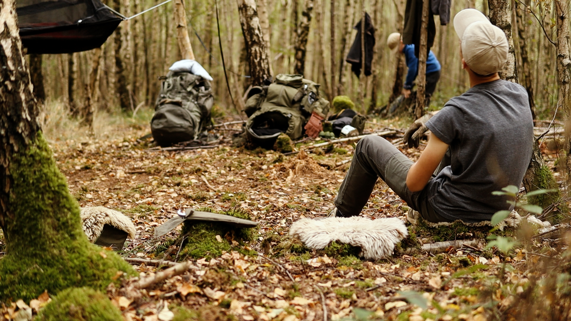 Person bearbeitet Holz im Wald für den Bau einer Lagerbank – DIY Bushcraft beim Familien-Camping