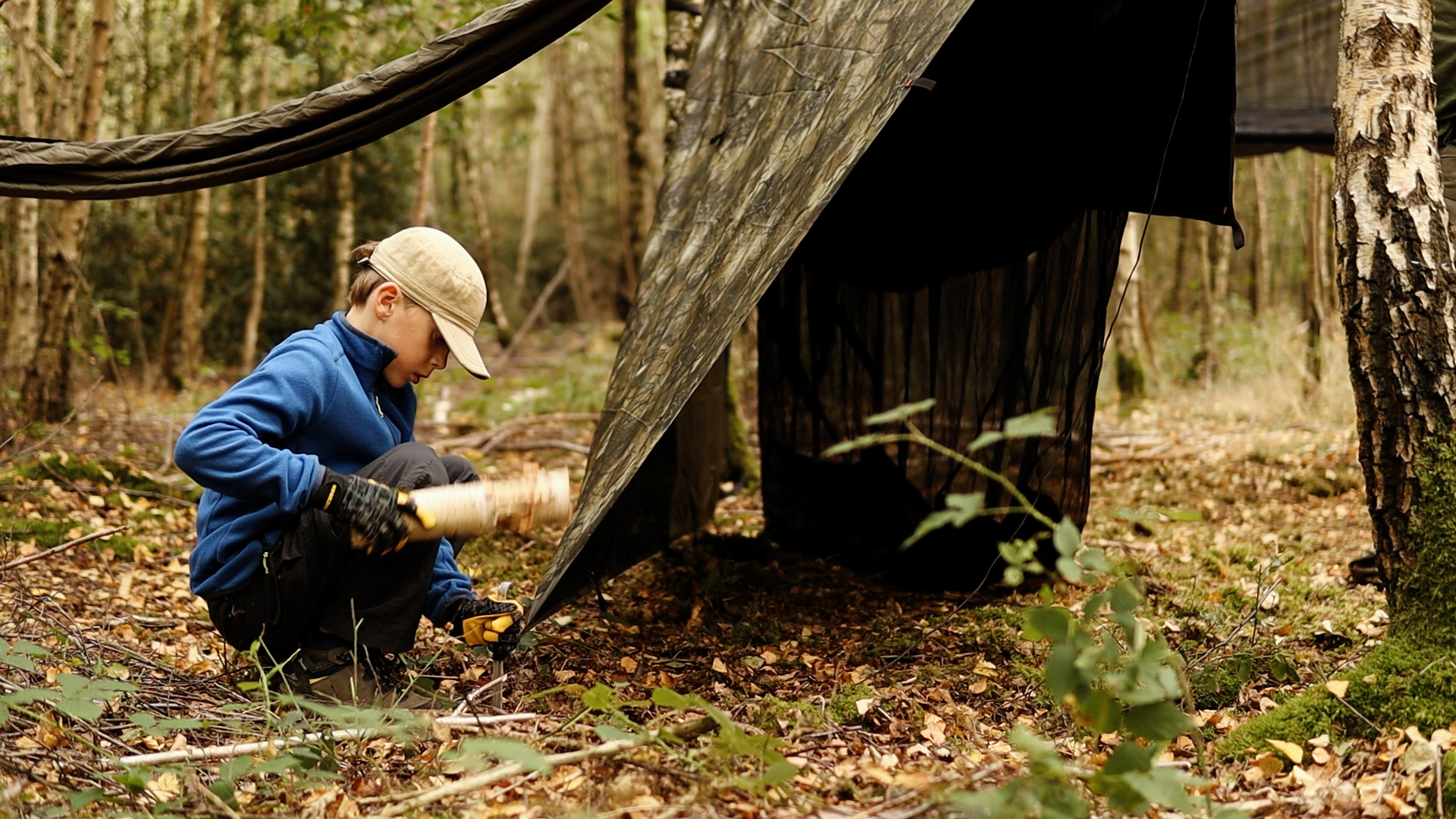 Person spannt ein Tarp im Wald auf – Tarp-Setup beim Hammock Camping mit Kindern
