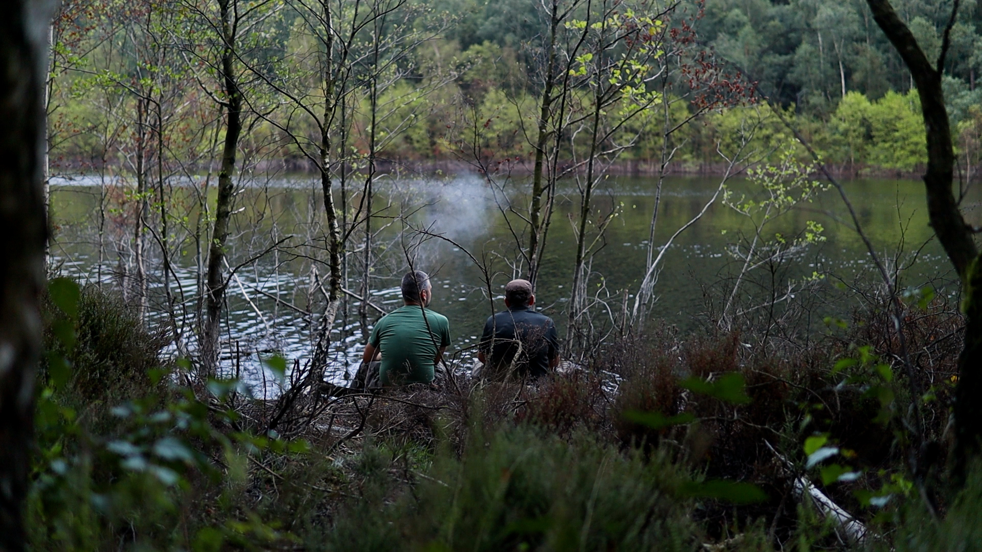Zwei Männer sitzen in der Abenddämmerung am ruhigen See