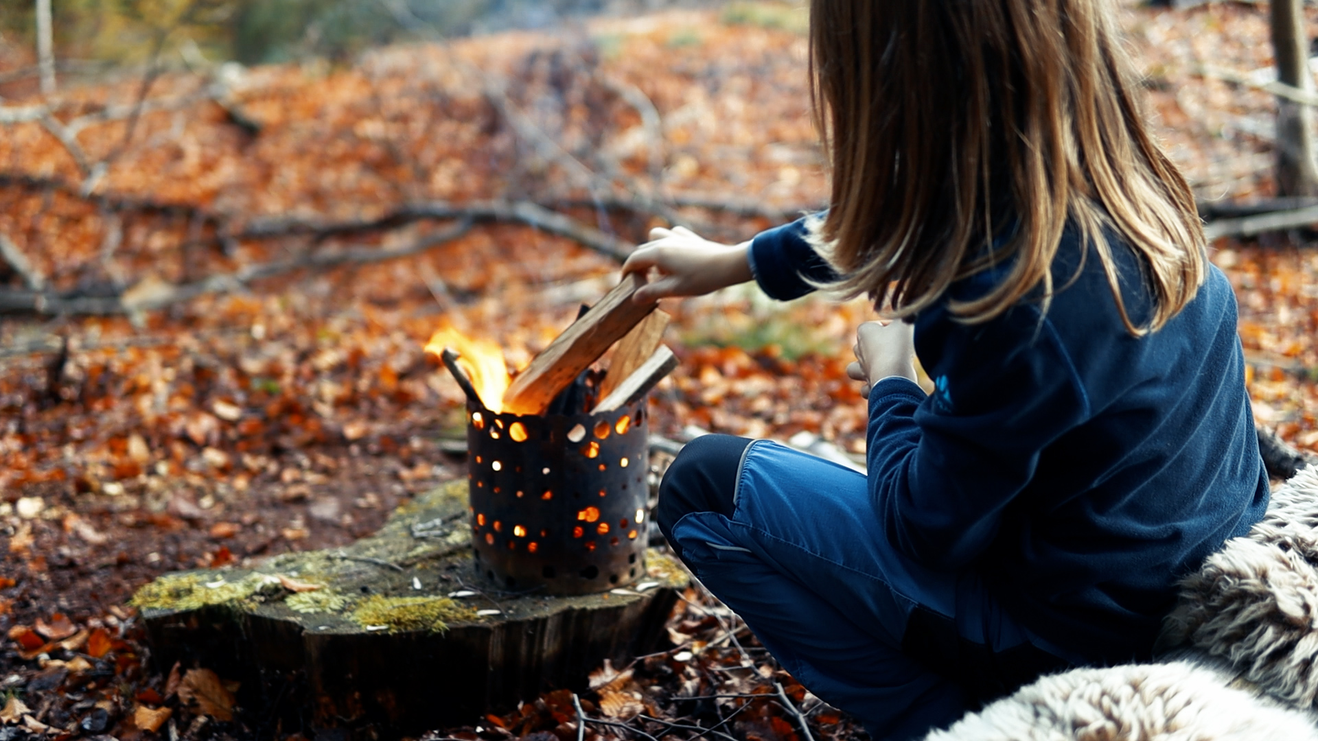Kind legt Holz in den X-Fire — Feuermachen leicht gemacht