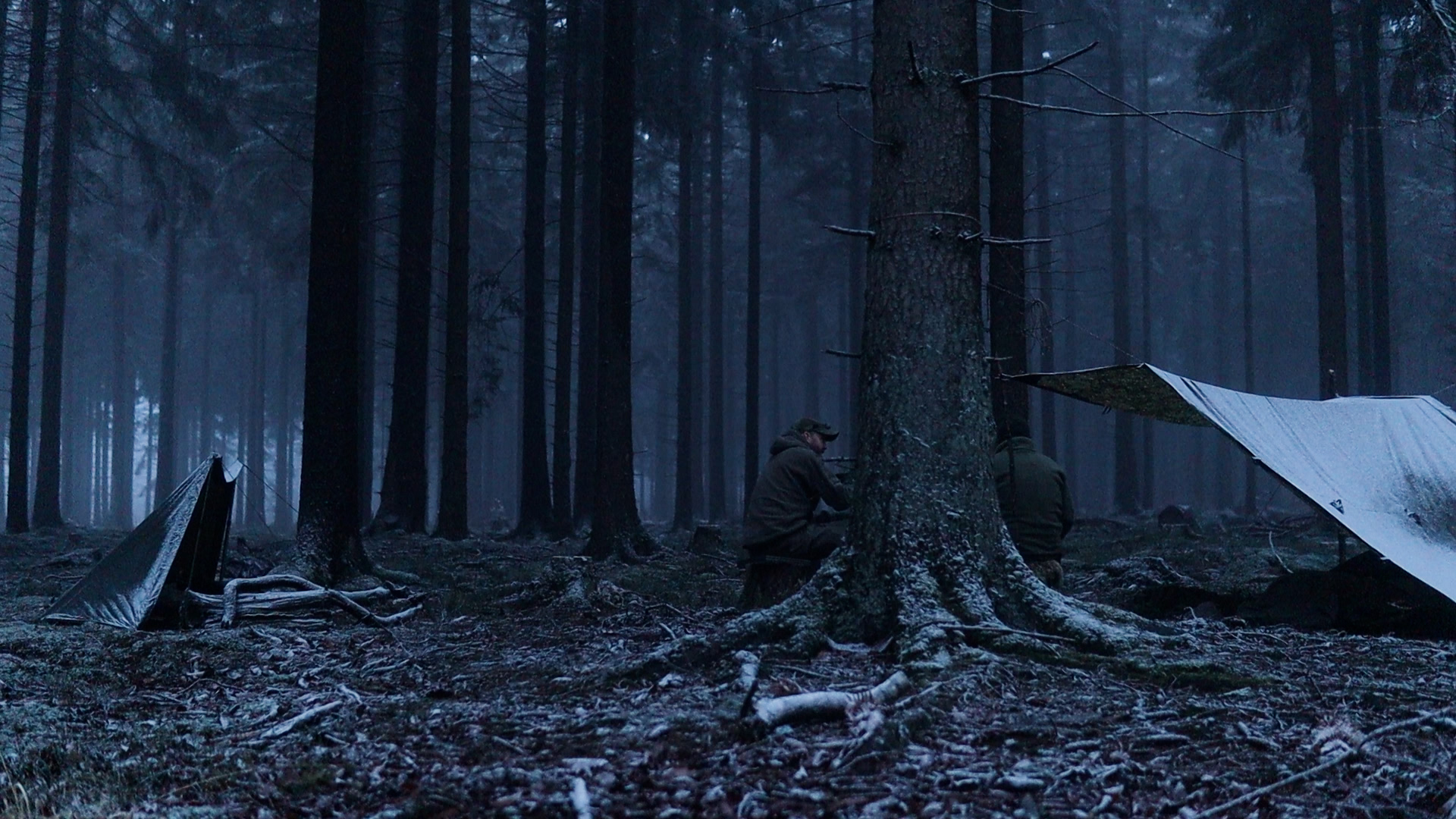 Zwei Tarp-Shelter im Morgengrauen eines Winterwalds beim gemeinsamen Bushcraft-Overnighter