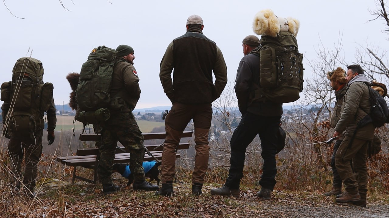 Gruppe macht Rast an einem Aussichtspunkt im verschneiten Hunsrück mit Blick über das Tal
