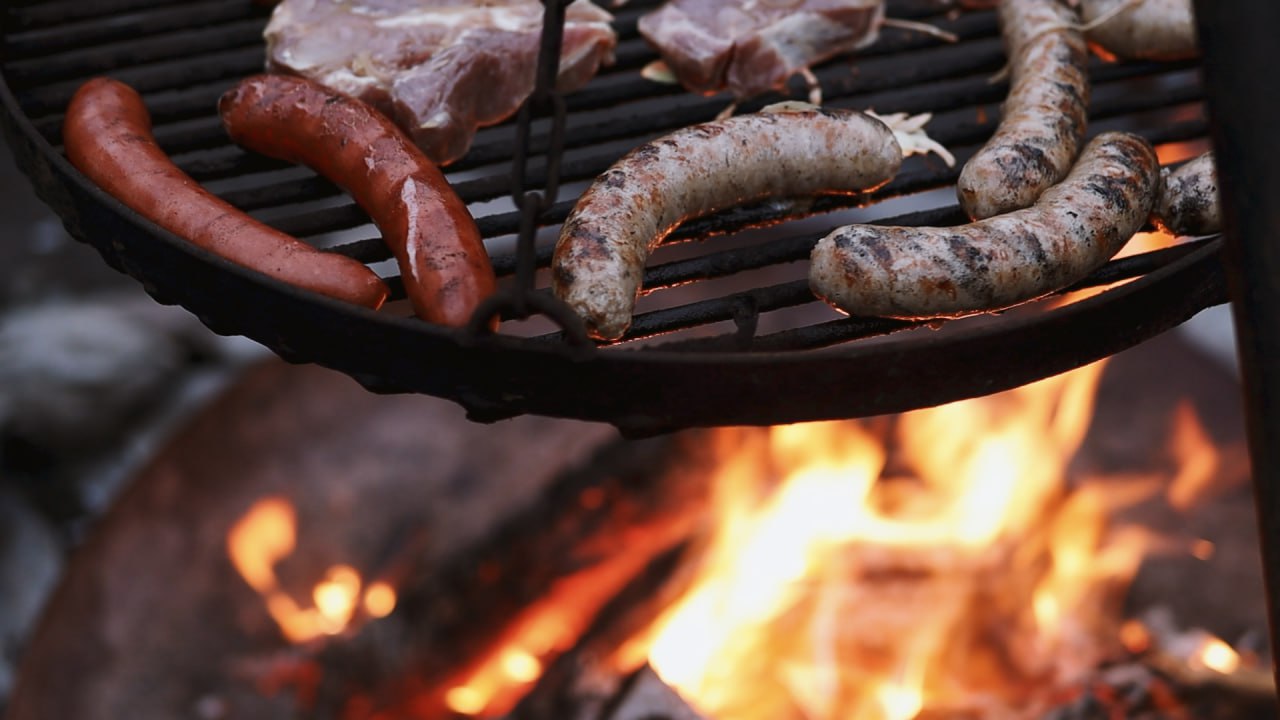 Würstchen und Fleischstücke auf einem Grillrost über offenem Lagerfeuer in der Schmidtburg