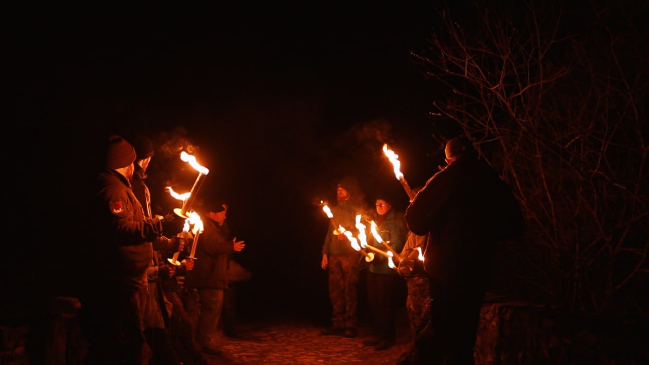 Gruppe mit brennenden Fackeln in der Schmidtburg bei Nacht – Winterbiwak im Hunsrück